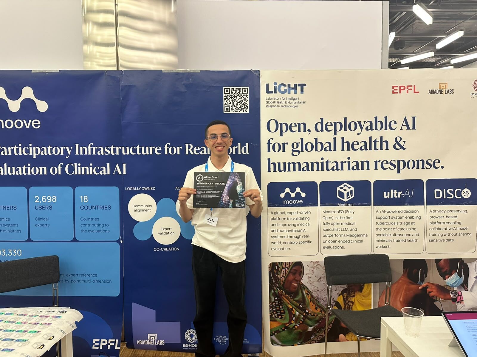 Omar at the LiGHT booth holding the AI for Good winner certificate