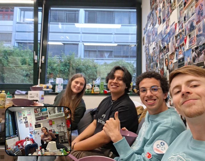 Four students smiling on a sofa in an office whose wall is covered in printed photos, one giving a thumbs up; an inset shows the rest of the room.