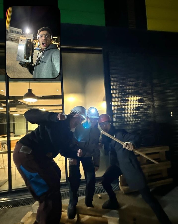 Three people in work clothes and head torches posing at night beside a stack of wooden pallets; an inset shows a student in safety glasses holding a power tool.