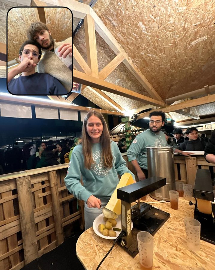 A student scrapes melted raclette onto a plate inside a wooden chalet; an inset shows two more people inside.