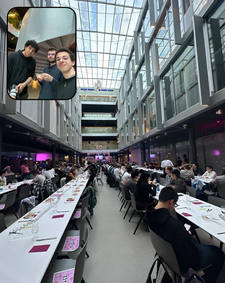 Long rows of dinner tables full of students under the glass roof of an atrium; an inset shows three of the staff.