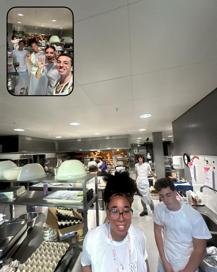 Two students in white aprons smiling in a large kitchen; an inset shows more of the kitchen team.